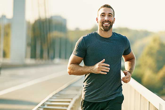 Attractive man jogging over a bridge