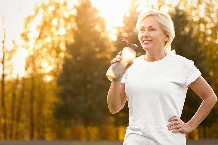 Middle aged woman drinking while exercising outside